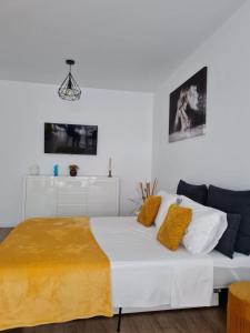 ein weißes Bett in einem weißen Zimmer mit gelben Kissen in der Unterkunft Apartament Luca P4B Oradea Prima Residence in Oradea