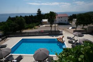 una piscina con sillas y sombrillas y una piscina en Apartments Mila, en Klenovica