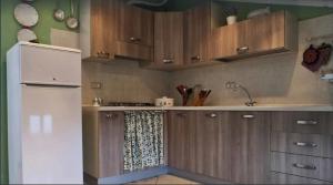 una cucina con armadi in legno e frigorifero bianco di Casa di Claudia ad Arnasco