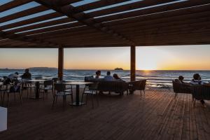 mensen aan tafels op het strand bij zonsondergang bij Hotel Punta Tipa in Trapani