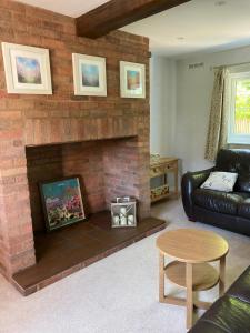 a living room with a brick fireplace and a couch at Honeysuckle Cottage in Hereford