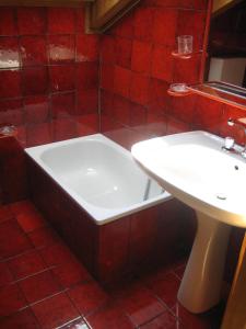 a red tiled bathroom with a tub and a sink at Appartamenti Decrestina in Campitello di Fassa