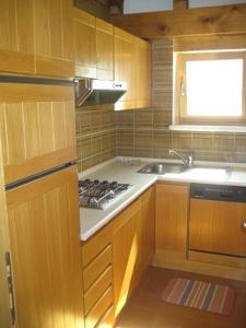 a kitchen with wooden cabinets and a stove and a sink at Appartamenti Decrestina in Campitello di Fassa