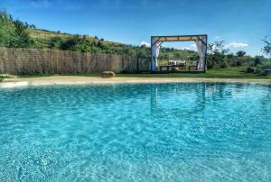una gran piscina de agua azul con un arco en el fondo en Masía el Cabrero en Villarroya de los Pinares