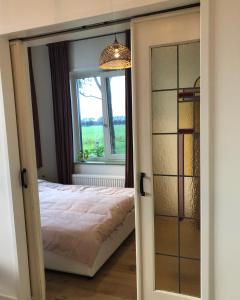 a bedroom with a bed and a window at Huisje op Bioboerderij, kust, polder en rust in Hoofdplaat