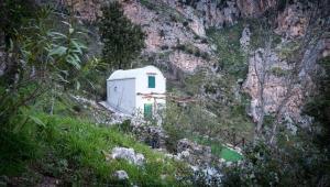 un pequeño edificio blanco en el lateral de una montaña en La Casetta Nel Bosco, Amalfi, en Amalfi