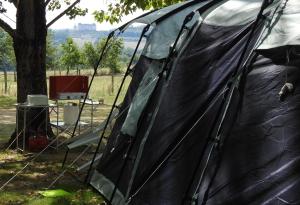 une tente noire assise dans un champ à côté d'un arbre dans l'établissement Camping Belle Vue, à Boisseuilh