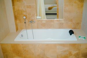 a bath tub in a bathroom with a mirror at Hotel Amel Aceh in Banda Aceh