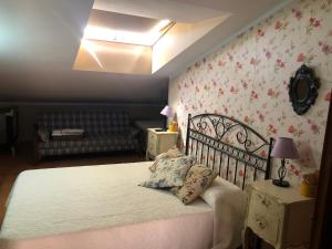 1 dormitorio con 1 cama blanca con flores en la pared en Hostal La Caballeriza en Malpartida de Cáceres