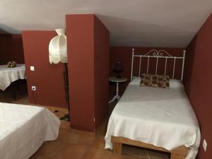 1 dormitorio con 2 camas y pared roja en Hostal La Caballeriza, en Malpartida de Cáceres