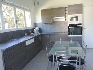 Villa de 250 m², climatisée, sur 2 niveaux au bord de l'eau - FR-1-100-243 في كافالير سور مير: مطبخ مع طاولة زجاجية وكراسي فيه