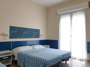 a bedroom with a bed with a blue and white comforter at Hotel Giannini in Rimini