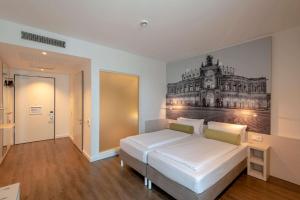 ein Schlafzimmer mit einem weißen Bett und einem Gemälde an der Wand in der Unterkunft Super 8 by Wyndham Dresden in Dresden