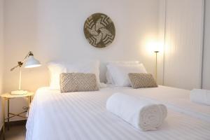 twee bedden met witte lakens en een klok aan de muur bij Casas do Mercado - Casa Nautilo in Angra do Heroísmo