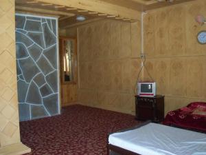 a bedroom with a bed and a tv on a wall at Manila Huts in Naran