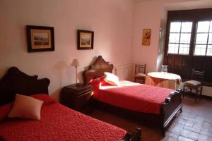 a bedroom with two beds and a table and a window at Casa El Carmen in Ciudad Real