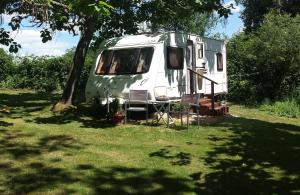 a green and white trailer parked under a tree at Camping Belle Vue in Boisseuilh