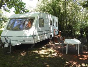 een witte caravan geparkeerd in het gras naast een tafel bij Camping Belle Vue in Boisseuilh
