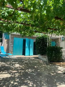 een blauw gebouw met blauwe deuren en een stoel bij Petite house in Starigrad-Paklenica