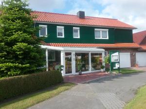 una casa verde con techo rojo en Fahrradurlaub in Ostfriesland für 4 Personen, en Utarp