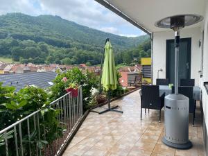 balcone con ombrellone, tavolo e sedie di Ferienwohnung Nuß ad Annweiler am Trifels