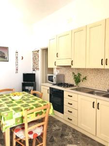 a kitchen with white cabinets and a table with chairs at Sunset Salentorelax San Gregorio in Marina San Gregorio