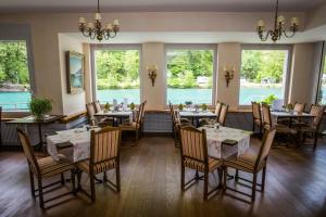 uma sala de jantar com mesas, cadeiras e janelas em Hotel Du Lac em Interlaken