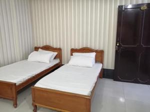 Duas camas individuais num quarto com lençóis brancos em Saif Hotel em Bālākot