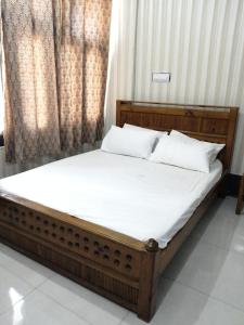 uma cama com lençóis brancos e almofadas num quarto em Saif Hotel em Bālākot