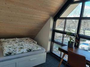 a bedroom with a bed and a desk and windows at Vakantiehuis met hottub en barrelsauna in Ommen