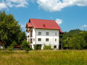 a large white building with a red roof at Pensiunea Magda in Câmpulung Moldovenesc