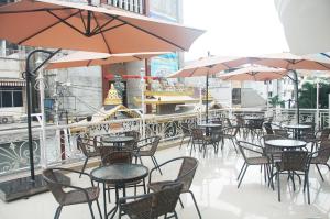 an outdoor patio with tables and chairs and umbrellas at Gandhi Inn in Medan