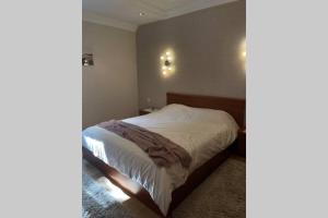 a bedroom with a bed with white sheets and lights on the wall at Cozy apartment in the Old Center of Prishtina in Pristina