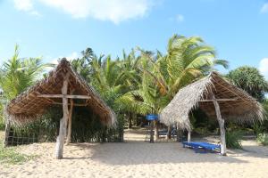dos sombrillas de paja y un banco azul en una playa en Lonely Beach Resort Tangalle, en Tangalle