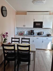 cocina con armarios blancos, mesa y sillas en Swan City Apartment, en Gulbene