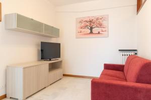 salon z czerwoną kanapą i telewizorem w obiekcie Rivierarent Lilium e Magnolia w mieście Pietra Ligure