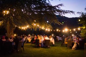 a group of people sitting at tables under a tree with lights at Maison CHILO in Barcus +43 photos
