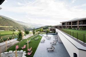 - une vue depuis le balcon d'un hôtel avec des chaises et des tables dans l'établissement Das Mühlwald - Quality Time Family Resort, à Naz-Sciaves