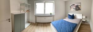 Schlafzimmer mit einem Bett mit blauer Bettwäsche und einem Fenster in der Unterkunft Moderne Ferienwohnung Hergolshausen in Waigolshausen