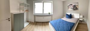 a bedroom with a bed with blue sheets and a window at Moderne Ferienwohnung Hergolshausen in Waigolshausen