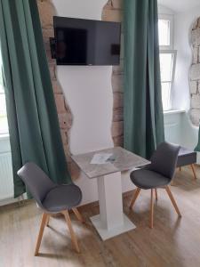 2 sillas y mesa con TV en la pared en Gästehaus Leonie, en Ebrach