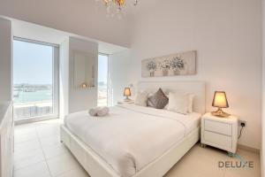 a white bedroom with a large bed and a large window at Stylish 1BR at Cayan Tower Dubai Marina by Deluxe Holiday Homes in Dubai