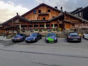 un grupo de cuatro coches estacionados frente a un edificio en Hotel l'Ecureuil, en Auron