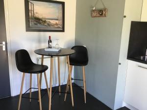 een kleine tafel met twee zwarte stoelen en een fles wijn bij Appartement Achterom in Hollum