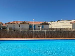 a swimming pool in front of a fence and a house at Residence Plage Oceane in Biscarrosse-Plage