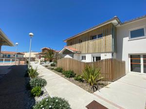 a house with a wooden fence next to a sidewalk at Residence Plage Oceane in Biscarrosse-Plage