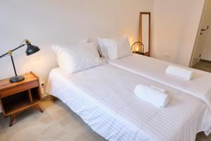 a bedroom with a large white bed with a lamp on a table at Casas do Mercado - Casa Sirius in Angra do Heroísmo