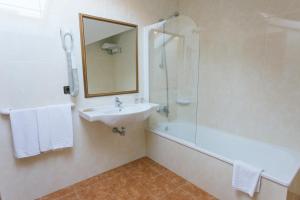 La salle de bains est pourvue d'un lavabo, d'une douche et d'un miroir. dans l'établissement Hotel O Castro, à Reboredo