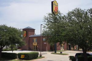 a red brick building with a sign on it at Super 8 by Wyndham Farmers Branch/North Dallas in Farmers Branch