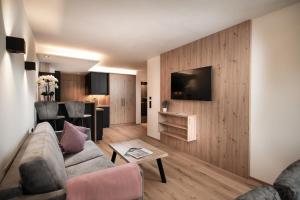 ein Wohnzimmer mit einem Sofa und einem TV an der Wand in der Unterkunft Appartement Alpenrot in St. Johann im Pongau